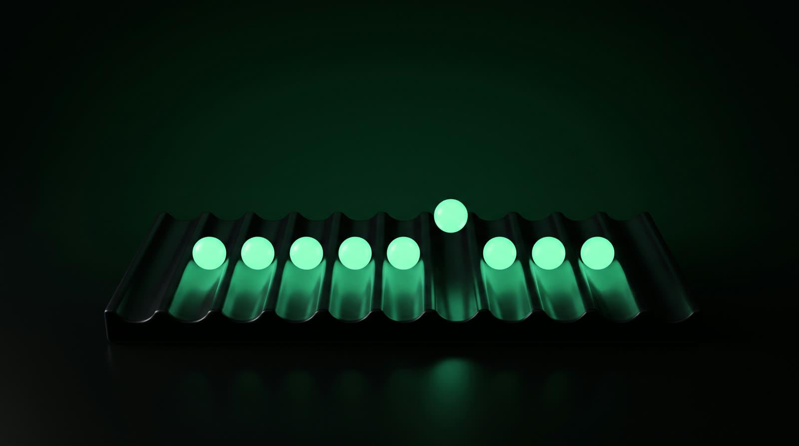 A ribbed dark tray holding a row of small glowing mint spheres, one lifted above the rest